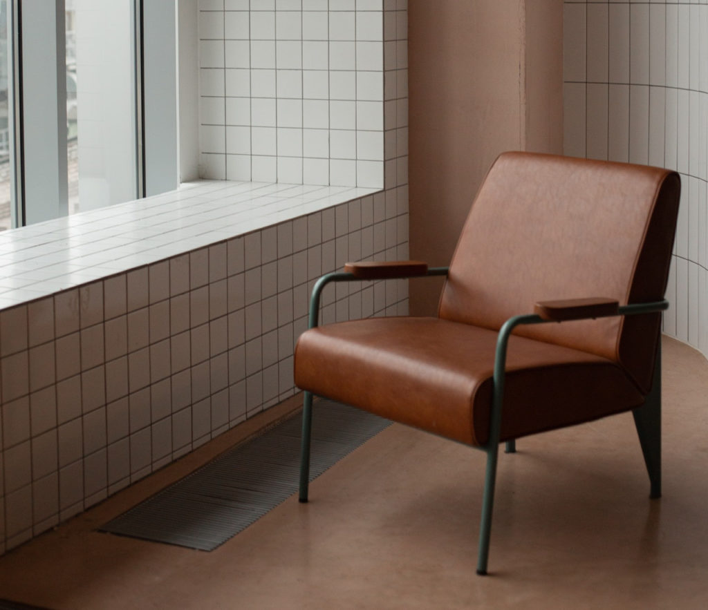 empty brown chair facing a window