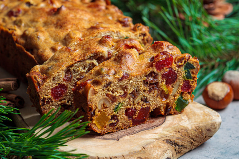 Traditional Christmas fruit cake on a wooden board in festive decoration, dark background